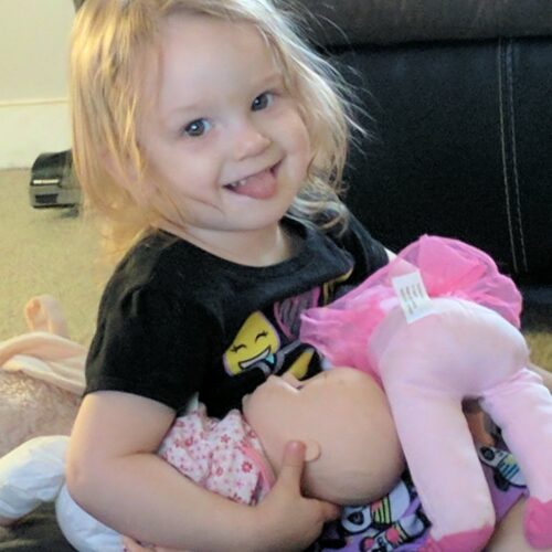 Little girl mimicking breast feeding with her doll